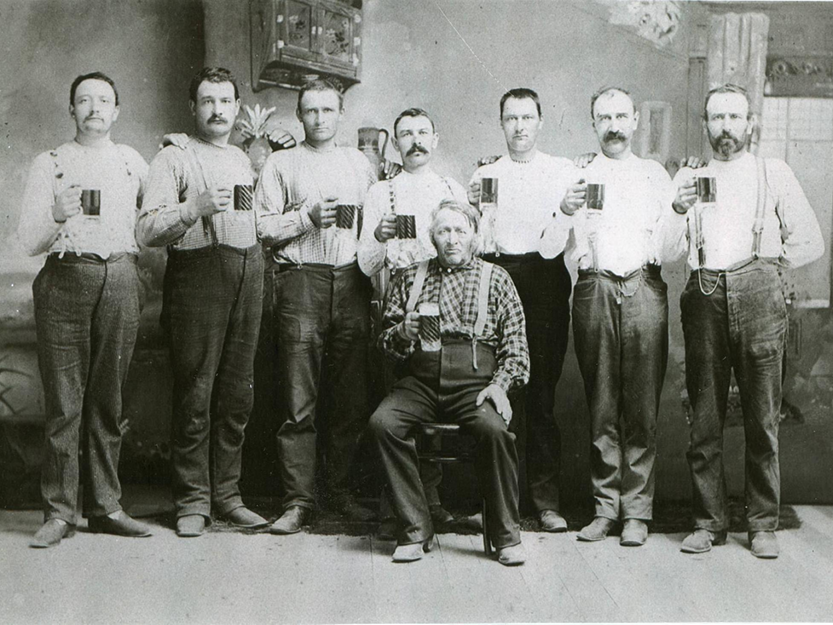 Black and white portrait of men holding tin mugs