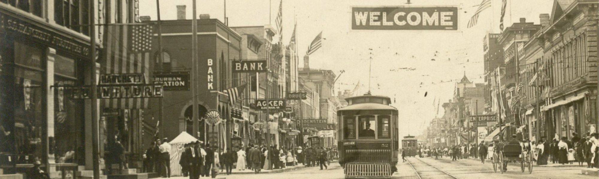 Black and white photo of downtown scene with pedestrians, carriages, and streetcars