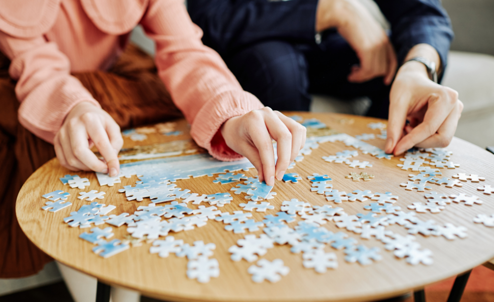 photo of two disembodied hands assembling a jigsaw puzzle