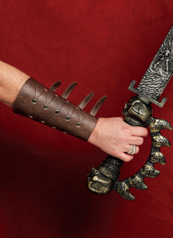 Picture of a forearm with leather-look bracer on a red background, wielding a spiked blade.