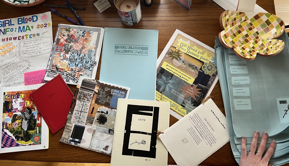 Photo of collection of "Girl Blood Info" Zines on a wooden table. 
